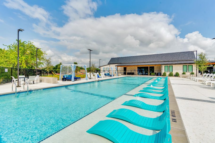 a pool with blue lounge chairs and a sunshade at The parcHAUS at Firewheel Parkway